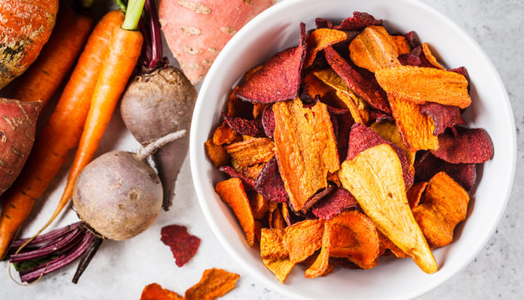 Bowl of healthy vegetable chips from beets, sweet potatoes and carrots on white background.