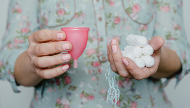 Woman holding tampons and menstrual cup in hands